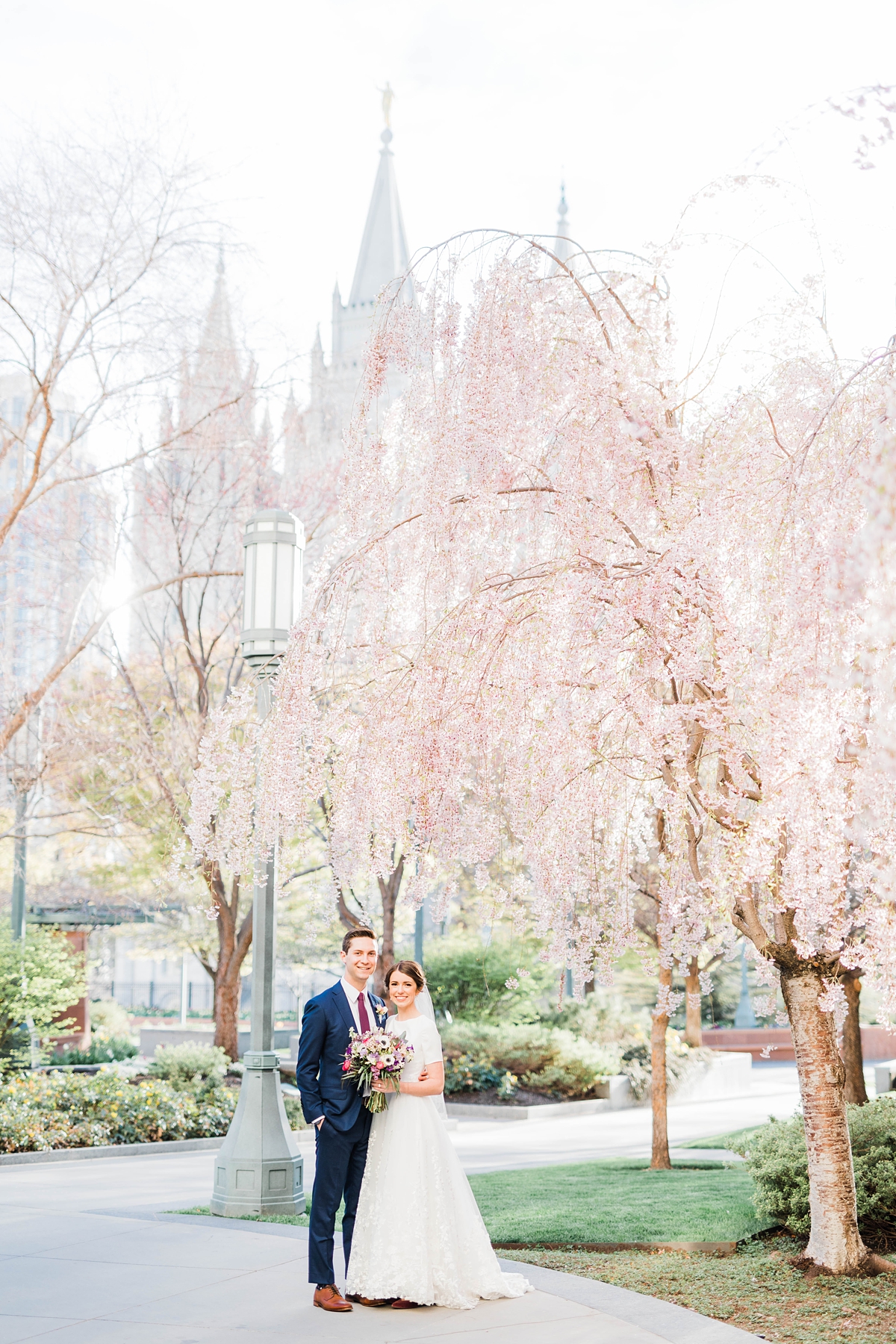 Spring wedding with cherry blossoms at the Salt Lake LDS Temple, modest lace wedding dress, purple flowers, utah wedding photography